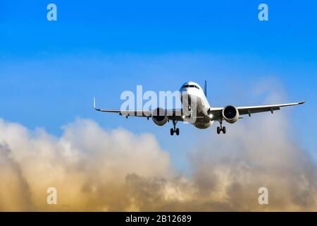 Passenger jet coming into land at an airport against blue sky and colourful clouds Stock Photo