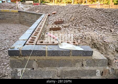 CARDIFF, WALES - JANUARY 2020: Bricklayer's trowel on top of a concrete block retaining wall around a garden. Stock Photo