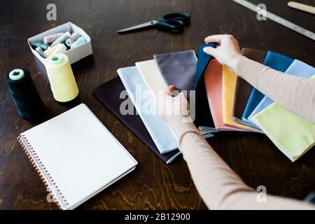 Hands of female fashion designer looking through textile samples on table Stock Photo