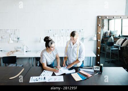 Two young fashion designers in casualwear choosing textile samples Stock Photo