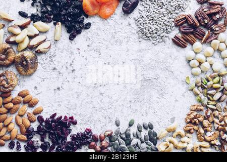 Various nuts seeds and dried fruits frame - pecans, hazelnuts, walnuts, pistachios, almonds, peanuts, pumpkin and sunflower seeds, cranberries, raisin Stock Photo