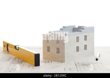 House of toy blocks with calculator and pen on construction plan - white background Stock Photo