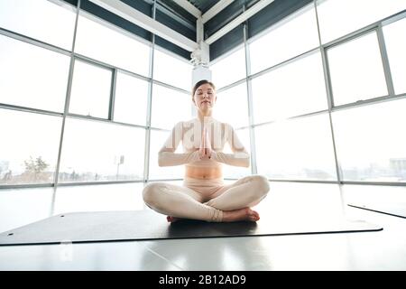 Serene girl in activewear sitting in pose of lotus during relaxation exercise Stock Photo