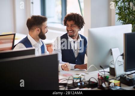 two young colleagues, multiethnic, talking and smiling at the office. business, modern, office, multiethnic, concept Stock Photo
