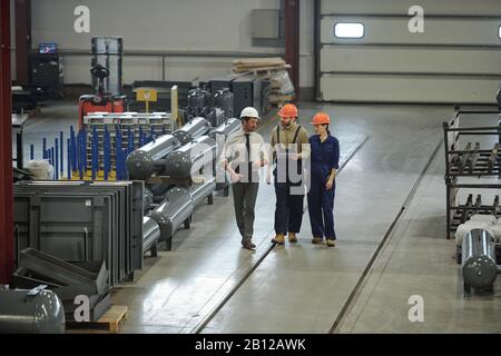 Group of contemporary professional technicians in workwear moving along workshop Stock Photo