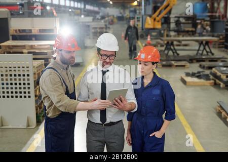 Group of young engineers looking at technical data on tablet display Stock Photo