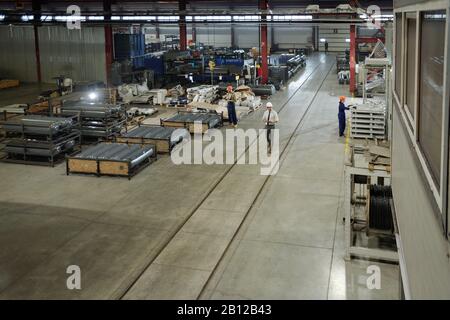 Large workshop of modern industrial plant with group of working engineers Stock Photo