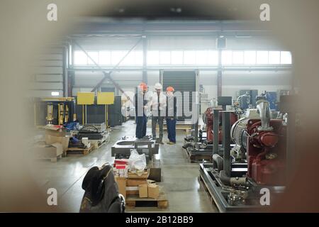Three engineers of industrial plant discussing technical sketch in touchpad Stock Photo