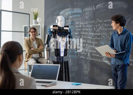 Contemporary young student with laptop making presentation of computer robot Stock Photo