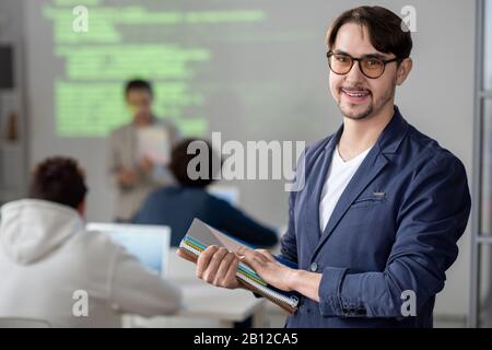 Young teacher on background of his students taking part in conference Stock Photo