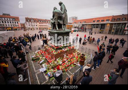 22 February 2020, Hessen, Hanau: People stand around the Brothers Grimm National Monument, where flowers were laid down to commemorate the attacks. In an allegedly racist attack, a 43-year-old German in Hanau, Hesse, shot several people and himself. Photo: Andreas Arnold/dpa Stock Photo