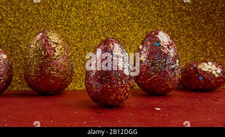 Selective focus of red golden eggs. A symbol of making money and successful investment on festive gold background Stock Photo