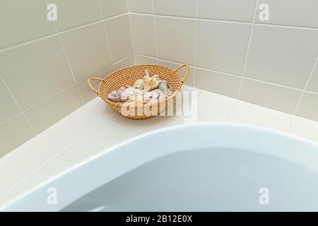 Basket of seashells sitting on edge of bathtub in seaside resort area. Stock Photo