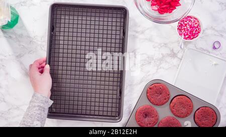 Flat lay. Step by step. Cooling red velvet cupcakes on a kitchen drying rack. Stock Photo