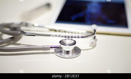 Closed up on Stethoscope and Tablet displaying brain activity scan laying on table, Medical workplace. Healthcare concept. Stock Photo