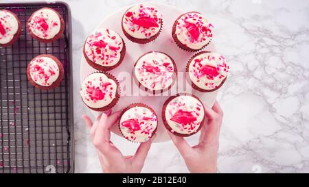 Flat lay. Step by step. Arranging red velvet cupcakes on a marble cake stand. Stock Photo