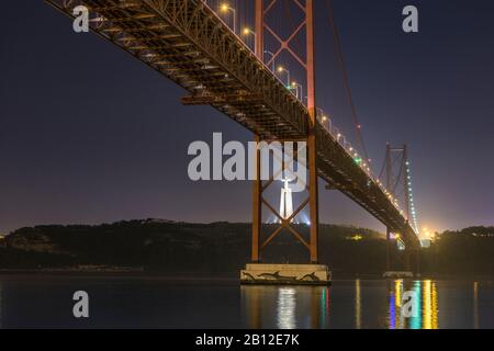 Night shot of Ponte 25 de Abril (bridge) and Cristo Rei (Christ statue in Almada), Lisbon, Portugal Stock Photo