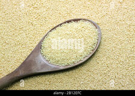 couscous in wooden spoon on kitchen table Stock Photo