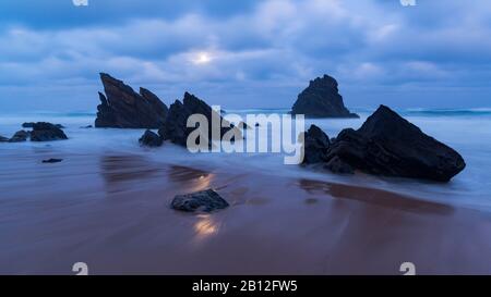 Moonlight on sandy beach with rock formations, Praia da Adraga, Sintra, Portugal Stock Photo