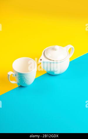 Tea pot and tea mug on a yellow and blue background Stock Photo