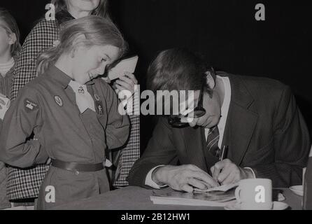 1960s, historical, British television presenter and entertainer, Leslie Crowther at a charity fete signing an autograph for a young brownie or girl guide, London, England, UK. A popular entertainer, especially with young people, Crowther was well-known as the presenter of the famous childrens' programme 'Crackerjack' and on BBC Radio One, 'Junior Choice'. He also presented 'Meet the Kids', a Xmas programme about a children's hospital ward. Stock Photo