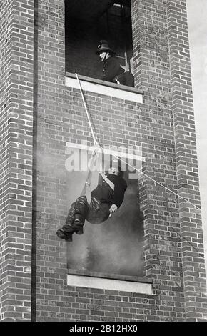 1970s, historical, a fireman in a harness and pulley escaping from a smoke-filled brick-built tower, during a training drill, Fleetwood, England, UK. Stock Photo