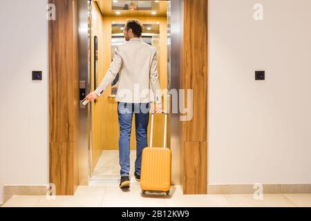 Modern businessman entering the elevator with luggage. Business and travel concept. Stock Photo