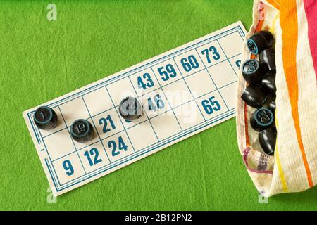 The Card lotto with black barrel from bag on green background. The Desk play. Stock Photo