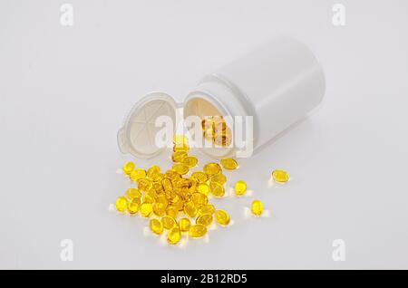 Yellow pills from a white container isolated on white background Stock Photo