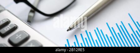 Silver pen with paper chart and glasses lie in office table Stock Photo