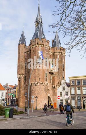 Zwolle, Netherlands, February 21, 2020: People crossing city gate Sassenpoort on bikes in ancient city centre Zwolle, Overijssel in the Netherlands. Stock Photo