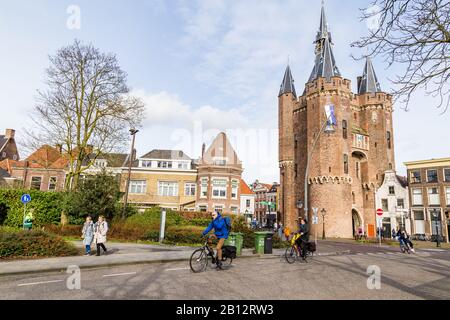 Zwolle, Netherlands, February 21, 2020: People crossing city gate Sassenpoort on bikes in ancient city centre Zwolle, Overijssel in the Netherlands. Stock Photo