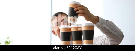 Stupid office clerk making huge tower out of paper cups Stock Photo