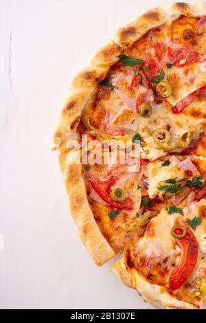 Half pizza with cheese, ham meat, tomato and parsley on white wooden background, copy space, top view Stock Photo