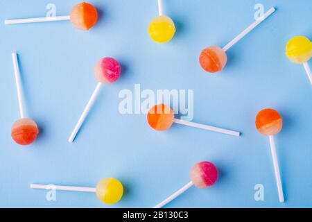 Scattered lollipop candies on blue background, top view Stock Photo