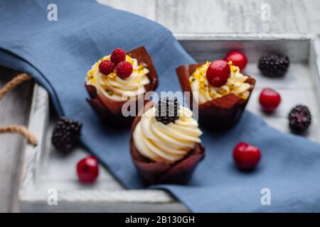 muffins with Belgian chocolate and white chocolate cream and mascarpone with berries on a wooden tray Stock Photo