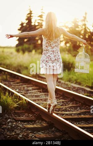 Young woman in dress balancing on a railway track Stock Photo