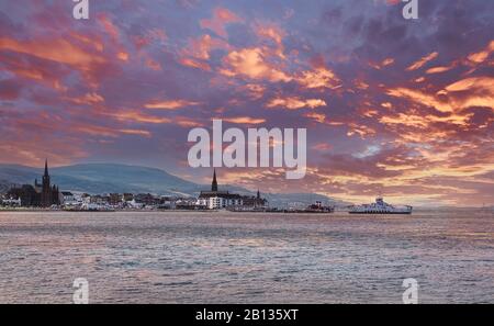 The local car ferry berthing at largs in Ayrshire. The Paddle steamer can be seen in the back ground all at sunset with blazing red skys. Stock Photo
