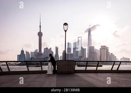 Bridal couple in front of skyline,The Bund,waterfront,sunrise,Shanghai,China Stock Photo