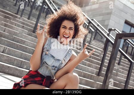 Young woman in the city street standing walking up stairs with penny board holding curl looking back camera happy Stock Photo