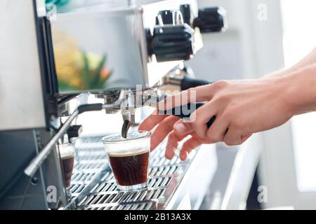 Coffee Passion. Young barista at coffee shop making espresso shot close-up Stock Photo