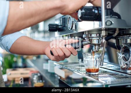 Young adult barista working in cafe, using coffee machine Stock Photo