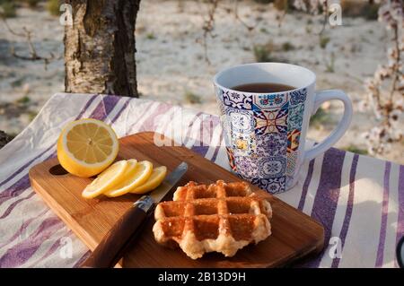 Morning picknic with cup of tea, fresh cut lemon and wuffle Stock Photo