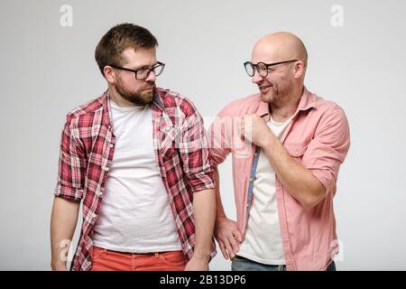 Bald man mockingly laughs at his bearded friend, who does not like a bad joke, and he looks hurt. Stock Photo