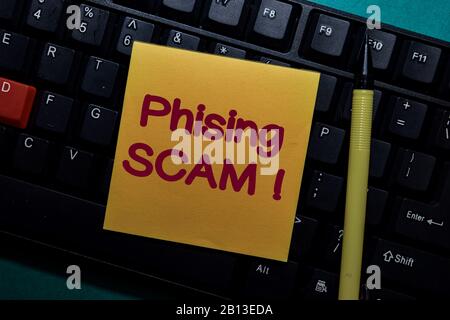Phising Scam! write on a sticky note isolated on Office Desk Stock Photo