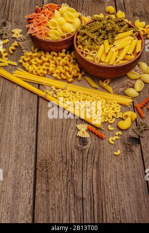Different types of pasta in ceramic bowls. Traditional Italian food, healthy eating concept. Rustic wooden table, copy space Stock Photo