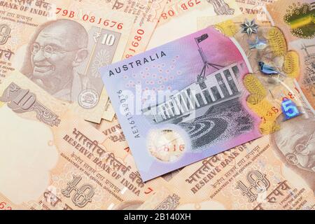 A close up image of an Australian five dollar bill with Indian ten rupee bank notes in macro