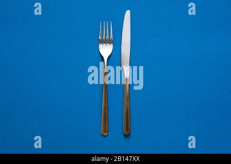 Fork and knife isolated on blue background.  Stock Photo