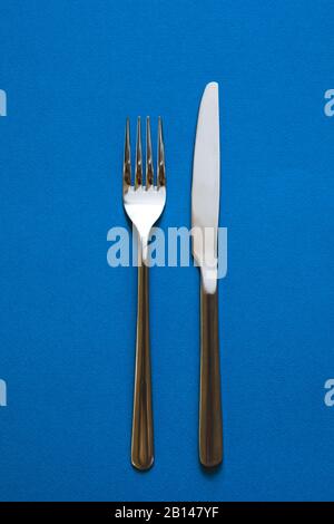Fork and knife isolated on blue background.  Stock Photo