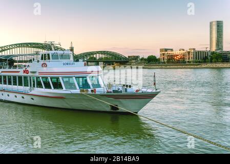 River cruise ship is anchored on the Rhine in Cologne, Germany. Hohenzollern Bridge, Hyatt Regency Hotel and KölnTriangle building in the background. Stock Photo